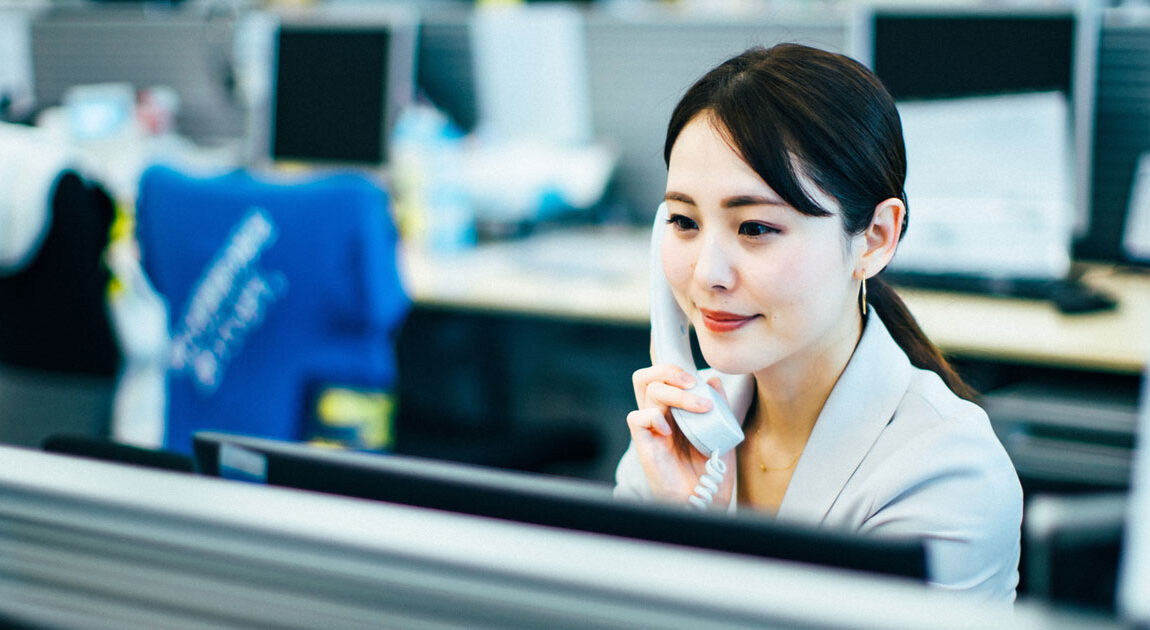 ビジネスフォンで電話をする女性のイメージ画像